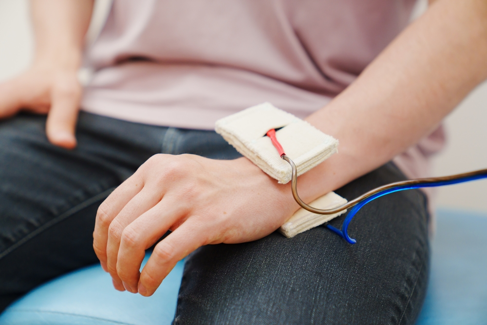 Patient undergoing IFT Physiotherapy with electrodes applied to the wrist for pain relief and muscle stimulation