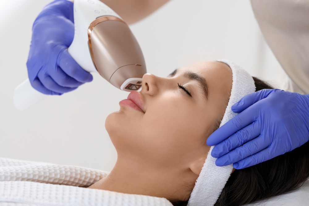 Professional performing laser hair removal on a patient's face in a clinical setting.